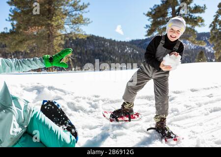 Un garçon de six ans avec des chaussures de neige tenant un grand ballon de neige. Banque D'Images