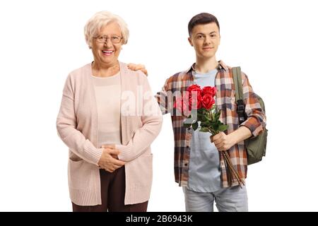 Adolescent étudiant en sexe masculin tenant une bande de roses rouges et se tenant à côté d'une femme âgée isolée sur fond blanc Banque D'Images