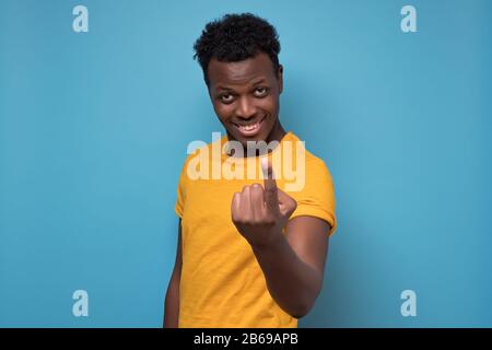 Un jeune homme africain américain qui fait des chaussures à venir. Venez ici. Studio tourné sur un mur bleu. Banque D'Images