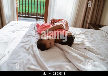 enfant asiatique et petite soeur embrassant ensemble quand on allongé sur le lit Banque D'Images