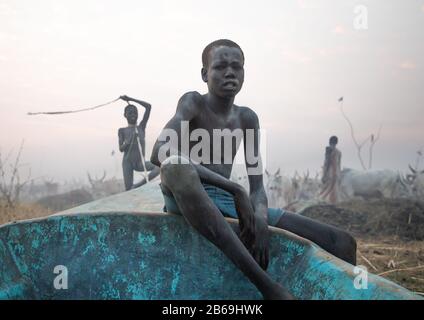 Un petit garçon de la tribu Mundari s'assoit sur un bateau, l'Equatoria central, Terekeka, Soudan du Sud Banque D'Images