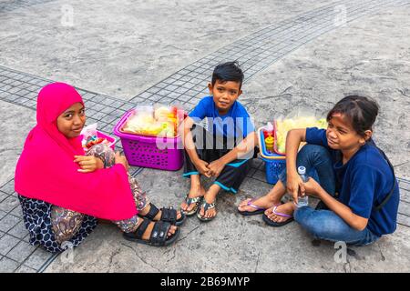 Enfants locaux vendant des fruits frais dans la rue, Sandakan, Bornéo, Malaisie, Asie Banque D'Images