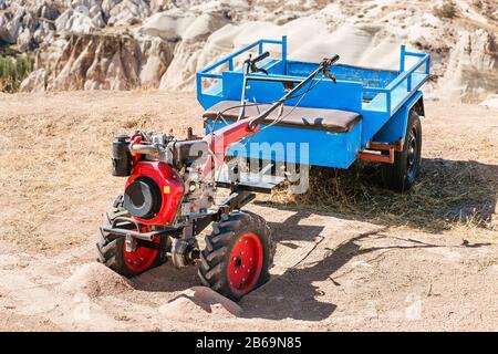 La petite charrue à moteur pratique de la machine agricole avec chariot se rapproche debout dans un paysage rural déserté dans le sable Banque D'Images