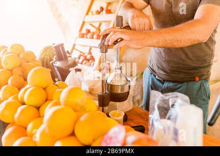 L'homme fait du jus fraîchement pressé sur une simple pression à la main dans le bar de fruits rustiques en Turquie Banque D'Images