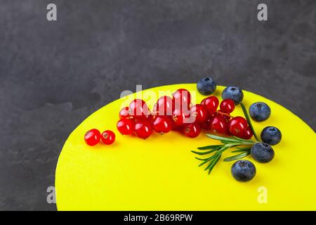 Gâteau jaune à la couche de citron sur la plaque en bois, décoré de bleuets et de cassis rouge sur fond sombre, espace de copie, place pour le texte, horizontal Banque D'Images