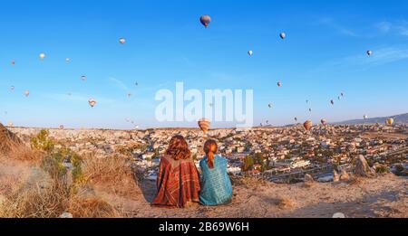 Couple d'amis voyageurs profitant de la vue sur la vallée avec de merveilleux ballons vol au-dessus de la vallée de la Cappadoce en Turquie Banque D'Images