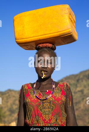 Portrait d'une femme de tribu Larim portant un jerrycan d'eau sur la tête, les monts Boya, Imatong, Soudan du Sud Banque D'Images