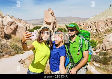 Groupe d'amis voyageurs profitant de la vue sur la vallée et faire selfie sur un téléphone avec la merveilleuse ville grotte de Zelve en Cappadoce en Turquie Banque D'Images