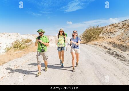 Un groupe de jeunes voyageurs actifs et lumineux se promener parmi les collines colorées du désert de tuff dans le parc national de Cappadoce, Turquie Banque D'Images