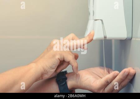 Près Des Mains d'une femme pompant du savon avec de la presse à savon liquide dans les toilettes pour se laver les mains. Concept De Nettoyage Et De Santé. Banque D'Images