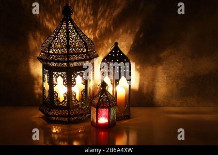 Lanternes arabes ornementales avec bougies brûlantes sur table illuminant la nuit, carte de vœux festive, invitation pour le mois Saint musulman Ramadan Kareem. Ift Banque D'Images