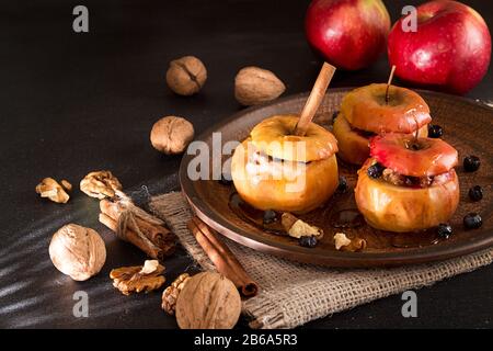 Pommes au four farcies aux noix et miel sur Brown sur la plaque sur fond noir. Banque D'Images