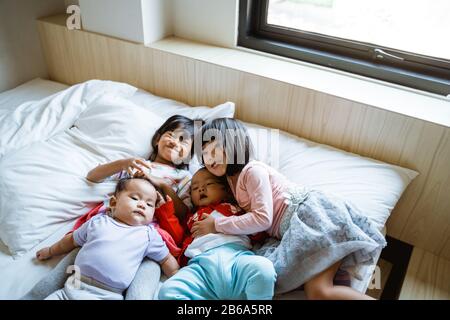 quatre enfants heureux de jouer et de blaguer au lit quand ils se réveillent Banque D'Images