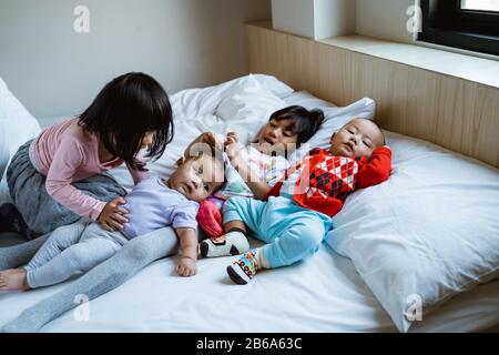 quatre enfants heureux de jouer et de blaguer au lit quand ils se réveillent Banque D'Images