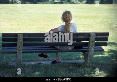 vue arrière d'une femme assise sur un banc de parc Banque D'Images