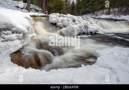 Les chutes d'Ocqueoc traversent la glace et la neige près de Rogers City dans le nord du Bas-Michigan pendant un hiver froid Banque D'Images