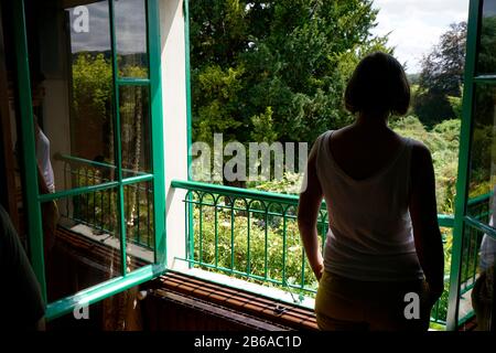 Un visiteur par la fenêtre de la chambre de la maison de Claude Monet avec le jardin en arrière-plan.Giverny.région de Normandie.France Banque D'Images