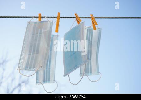 Masques médicaux bleus suspendus sur une ligne de vêtements avec des clothessons contre le ciel. Banque D'Images