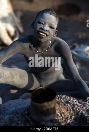 Un jeune garçon souriant de la tribu Mundari couvert de cendres pour repousser les mouches et les moustiques dans un camp de bétail, l'Equatoria central, Terekeka, Soudan du Sud Banque D'Images