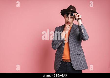 Portrait d'un jeune homme pensif séduisant portant une veste et un chapeau isolés sur fond rose Banque D'Images