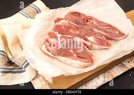 Biftecks d'agneau crus hachés sur parchemin, prêts à préparer le dîner. Banque D'Images