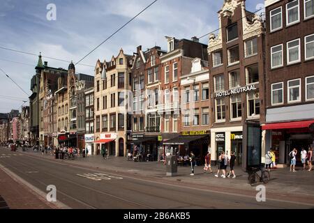 Vue sur les gens marchant sur l'avenue Damrak. Les bâtiments historiques et traditionnels et les boutiques sont dans la vue. C'est la rue principale où les gens arrivent Banque D'Images