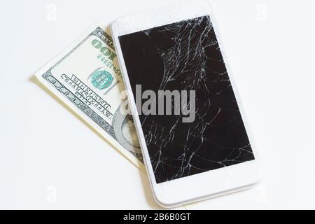 Téléphone portable avec écran cassé sur une facture de cent dollars. Paiement pour la réparation ou le remplacement du smartphone Banque D'Images