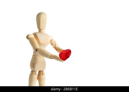 La figure en bois d'un homme tient dans ses mains un coeur rouge sur un fond blanc. Donne le cœur. Cadeau Saint-Valentin Banque D'Images