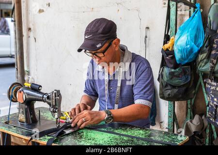 Fabrication et réparation de sacs à main et de produits en cuir à l'aide d'une ancienne machine à coudre dans la rue du centre-ville de Sandakan, Bornéo, district de Sabah, Banque D'Images