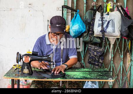 Fabrication et réparation de sacs à main et de produits en cuir à l'aide d'une ancienne machine à coudre dans la rue du centre-ville de Sandakan, Bornéo, district de Sabah, Banque D'Images