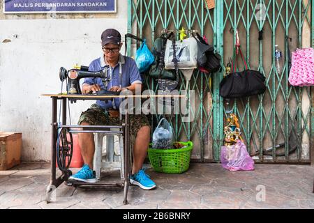 Fabrication et réparation de sacs à main et de produits en cuir à l'aide d'une ancienne machine à coudre dans la rue du centre-ville de Sandakan, Bornéo, district de Sabah, Banque D'Images