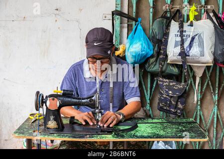 Fabrication et réparation de sacs à main et de produits en cuir à l'aide d'une ancienne machine à coudre dans la rue du centre-ville de Sandakan, Bornéo, district de Sabah, Banque D'Images