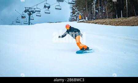 Jeune homme s'amusant à descendre la pente sur un snowboard Banque D'Images