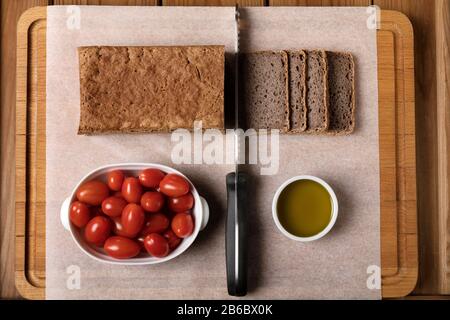 Pain de sarrasin sans gluten sur une planche à découper avec de l'huile d'olive et des tomates. Banque D'Images