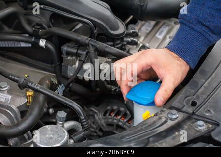 Gros plan sur les mains pour vérifier le niveau d'une rondelle en verre. Concept de réparation de voiture. Service automobile. Banque D'Images