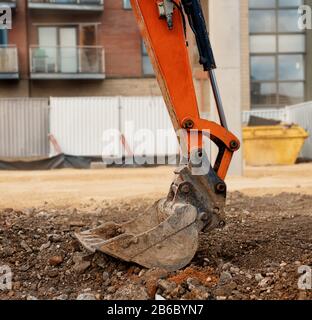 Gros plan d'un godet de pelle hydraulique orange placé sur le sol en position de sécurité Banque D'Images