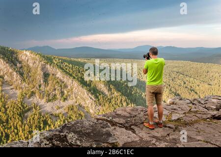 Jeune homme voyageur prenant une photo en montagne Banque D'Images