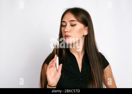 Maquilleuse professionnelle pose avec le pinceau à maquillage et produits de maquillage pour la publicité sur fond blanc. Banque D'Images