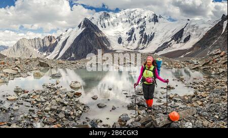 Une femme aventurière et grimpante près d'une montagne passe sur un glacier dans un casque et avec un sac à dos Banque D'Images