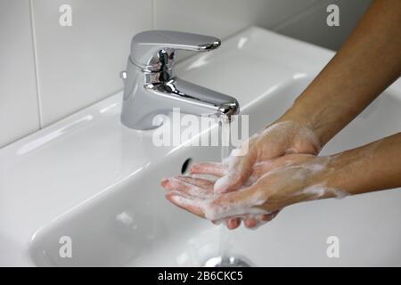 COVID-19 se laver les mains avec du savon sous le robinet avec de l'eau contre le coronavirus de Novel (2019-nCoV). Concept d'antiseptique, d'hygiène et de santé. Banque D'Images