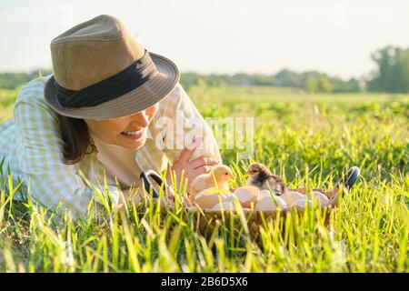 Panier avec poulets nouveau-nés, femme heureuse dans chapeau regardant des poussins de bébé Banque D'Images