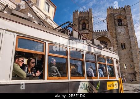 Lisbonne, Portugal - 8 mars 2020: Les touristes qui voyagent le célèbre tramway jaune 28 en face de la cathédrale de Lisbonne Banque D'Images