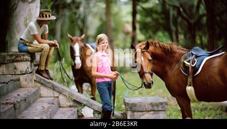 Teenage Girl standing with her young mère et deux chevaux. Banque D'Images