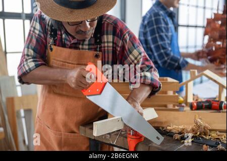 Charpenter travaillant sur des machines de travail du bois dans un atelier de menuiserie, produit en bois Banque D'Images