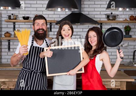 bonne journée en famille. famille sympathique dans la cuisine. cuisine saine à la maison. chef cuisinier pour enfants. espace de copie. faites tout ensemble. gagnants quotidiens. La mère et le père cuisiniers avec la fille. Aliments biologiques. Banque D'Images