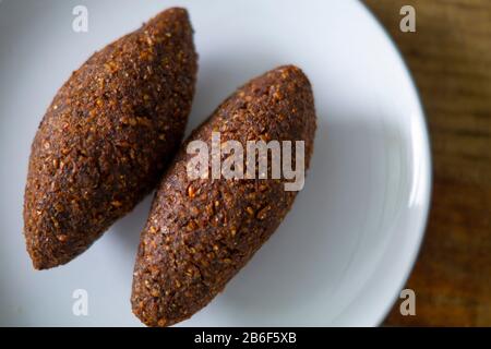 quipe, delicioso kibbeh frito con salsa de yogur en un bol servido en un plato de arcilla sobre una vieja mesa de madera oscura, receta clásica, vista Banque D'Images