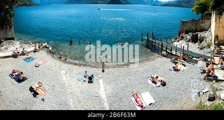 Touristes sur la plage de galets, le lac de Côme, Varenna, Lombardie, Italie Banque D'Images