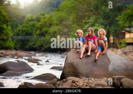 Les enfants en randonnée dans les montagnes des Alpes crossing river. Les enfants jouent dans l'eau à la montagne en Autriche. Vacances en famille au printemps. Petit garçon et fille sur le sentier de randonnée Banque D'Images