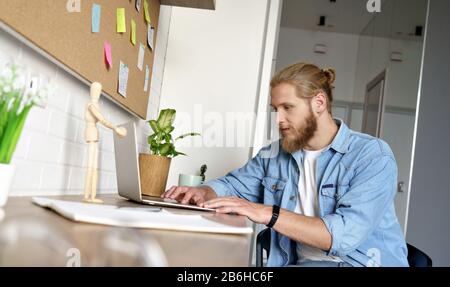 Jeune homme heureux travailler sur le type de projet email ordinateur portable à domicile concept copyspace. Banque D'Images