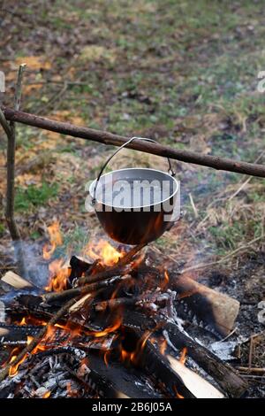 Chaudron au feu lors d'un voyage de randonnée. L'eau est bouillante dans un pot en métal sur feu de camp. Faire cuire du thé ou de la nourriture dans le camp dans la nature Banque D'Images